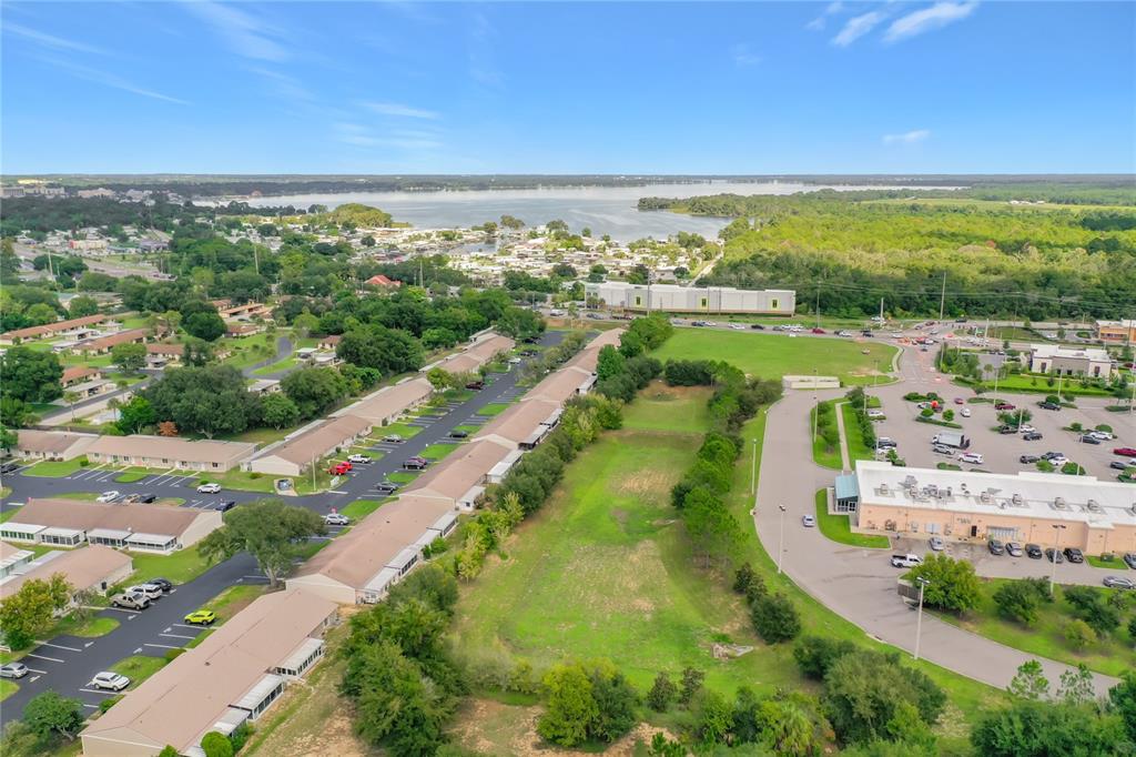 An aerial view shows a vacant grassy lot situated between a residential complex and parking lots — 30107 TAVARES RIDGE BOULEVARD UNIT 30107, TAVARES, FL