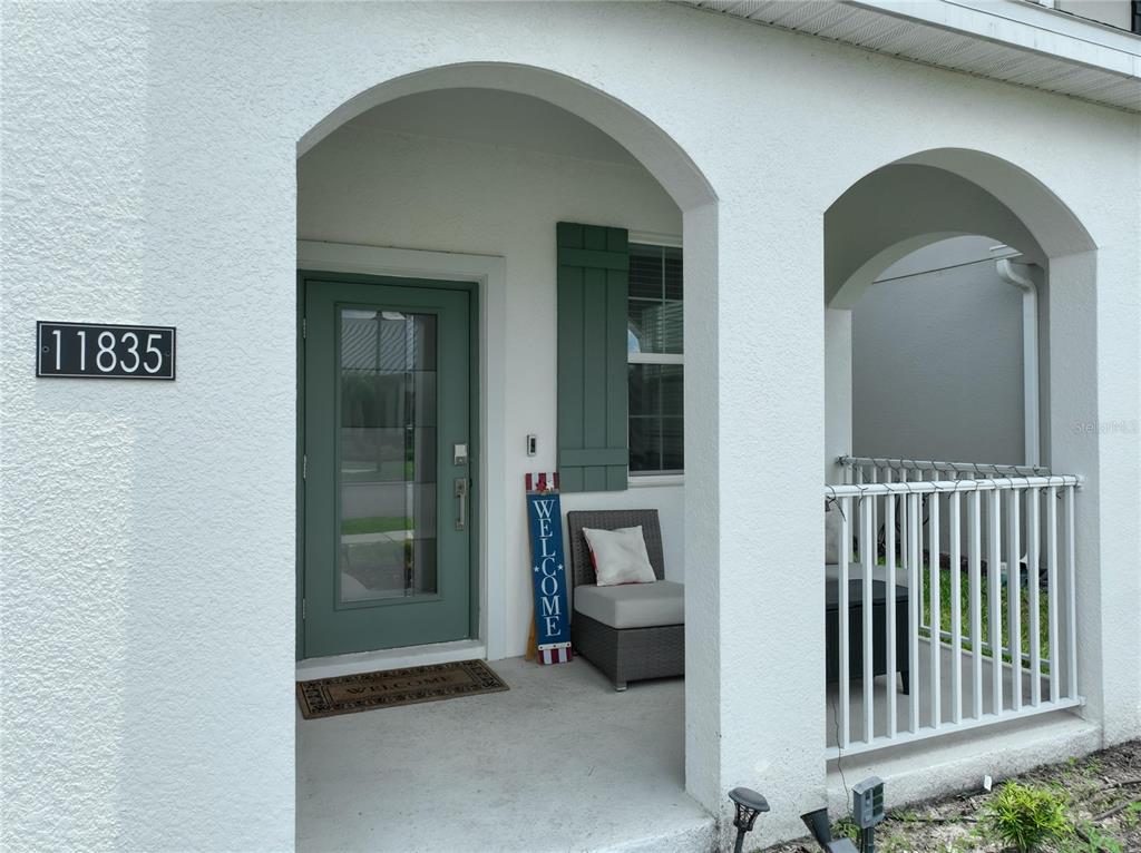 A covered entryway features a green front door, a welcome sign, and a small patio — 11835 BOLDFACE DRIVE, ORLANDO, FL