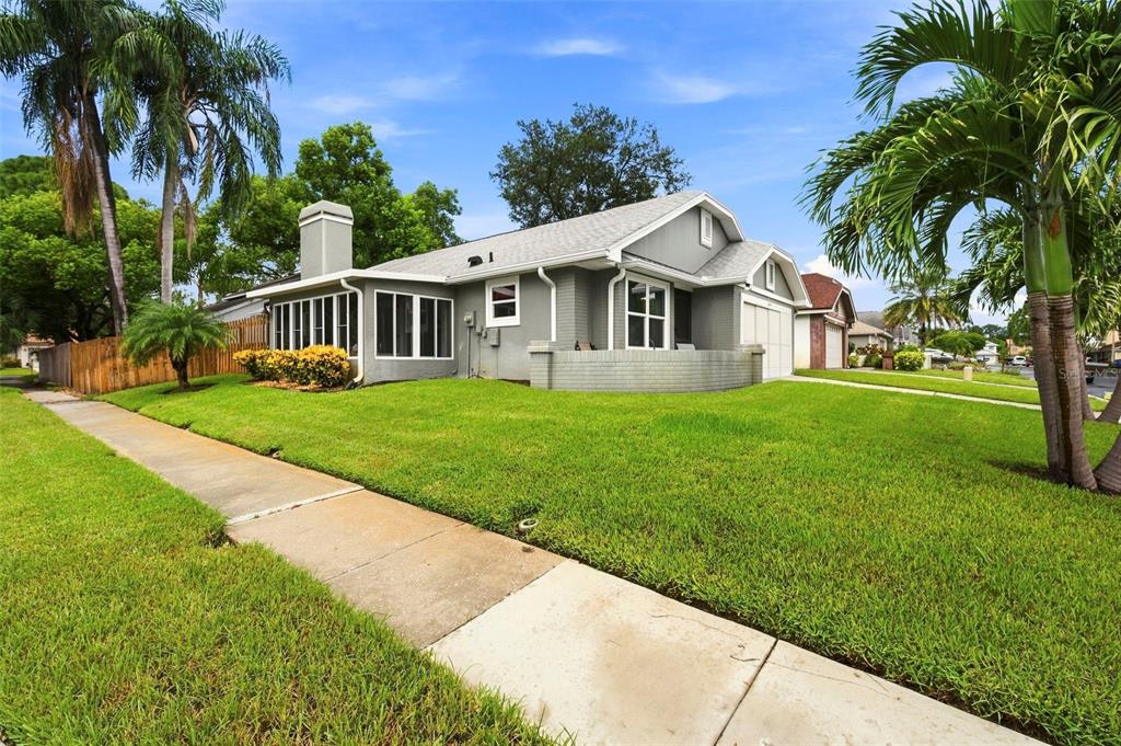 A gray single-story house with a screened-in porch, brick accents, and a manicured lawn — 2234 SPRINGFLOWER DR., CLEARWATER, FL