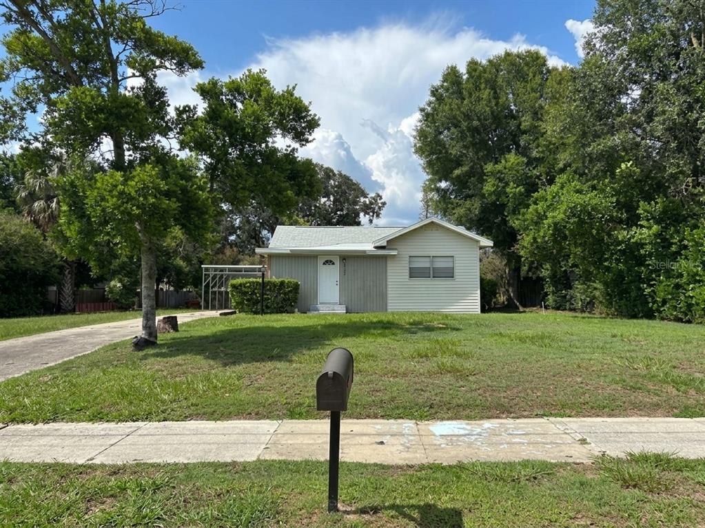 A single-story house with light-colored siding and a white front door sits on a grassy lot — 320 W BULLARD AVENUE, LAKE WALES, FL