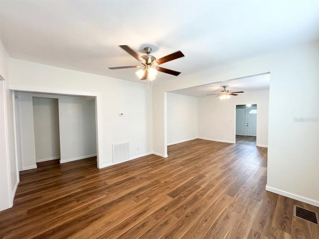 An interior view of a living area with wood-look flooring and two ceiling fans — 320 W BULLARD AVENUE, LAKE WALES, FL