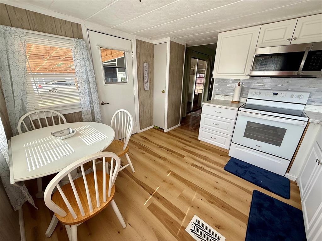 A kitchen and dining area with white cabinets, wood-look flooring, and a round table — 1360 IBIS DRIVE, ENGLEWOOD, FL