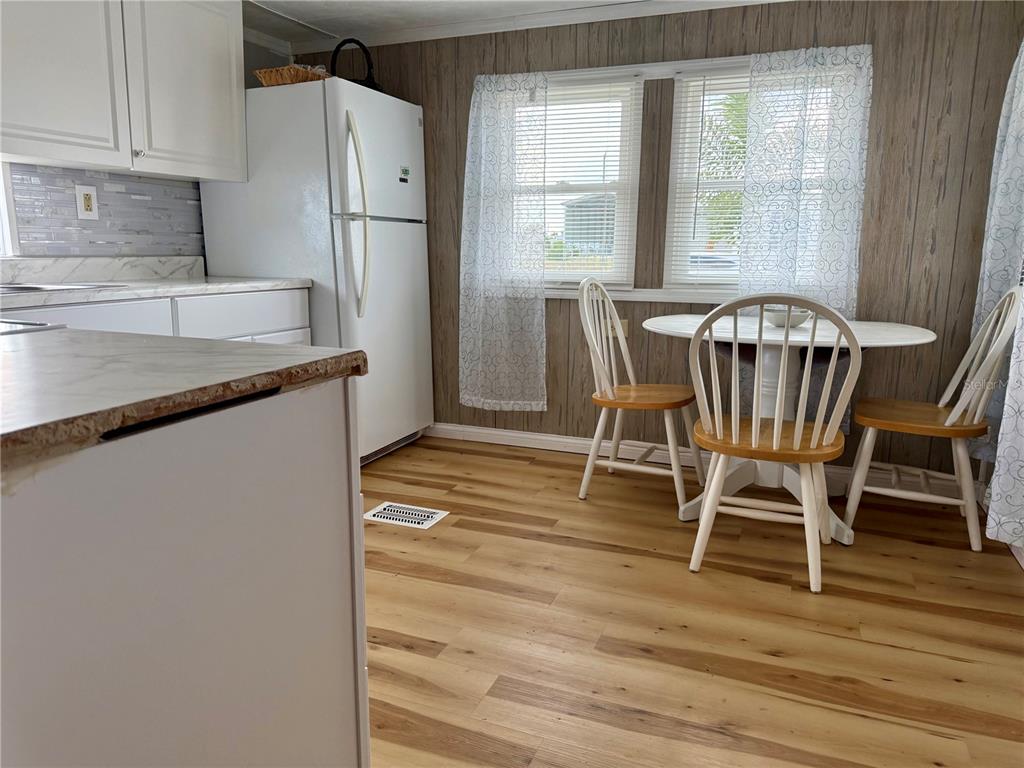 A kitchen with white cabinets, a white refrigerator, wood-look flooring, and a small dining set — 1360 IBIS DRIVE, ENGLEWOOD, FL