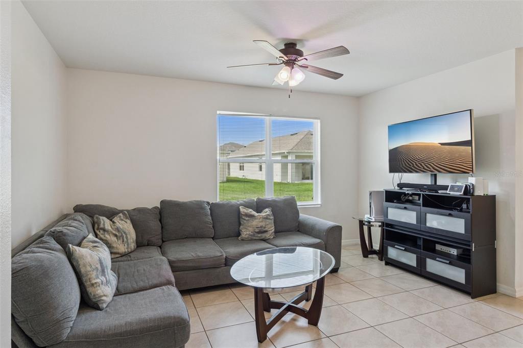 A living room features a gray sectional sofa, a glass coffee table, and tile flooring — 4013 SILVERSTREAM TERRACE, SANFORD, FL