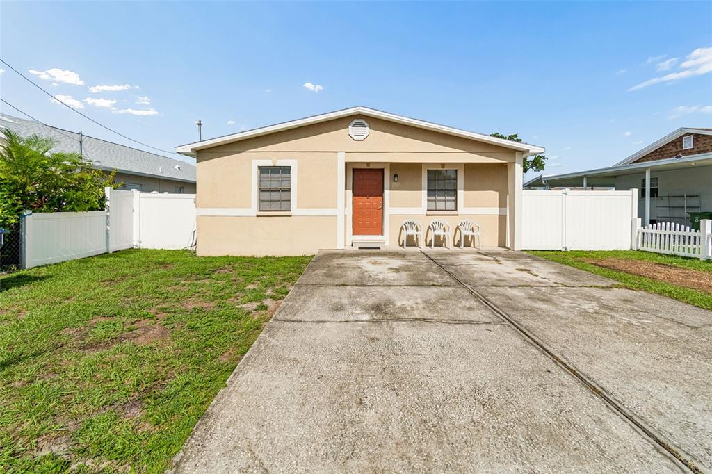 A single-story house with a tan exterior, a concrete driveway, and white vinyl fencing — 5120 N MATANZAS AVENUE, TAMPA, FL