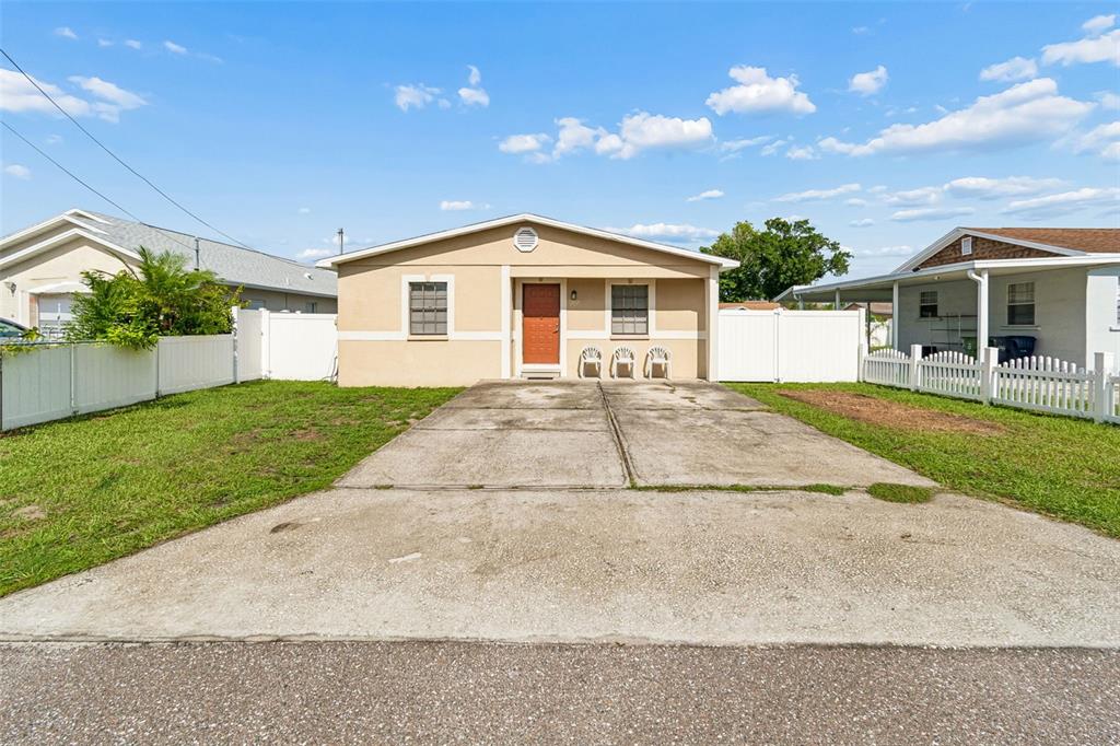 A tan single-story house with a concrete driveway and a white vinyl fence — 5120 N MATANZAS AVENUE, TAMPA, FL