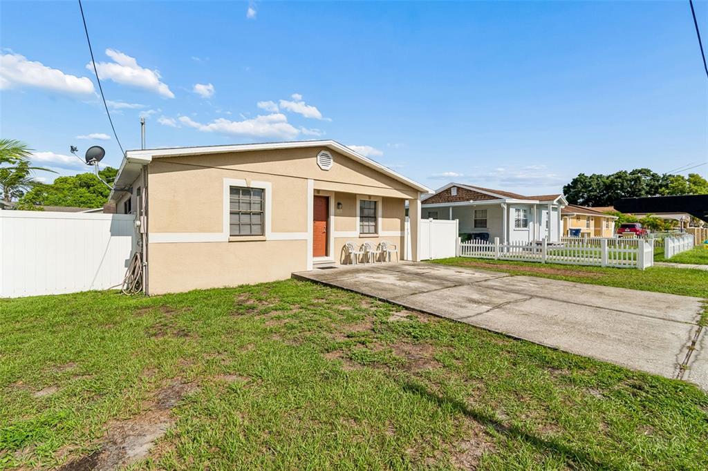 A single-story tan house with a concrete driveway and a white vinyl fence — 5120 N MATANZAS AVENUE, TAMPA, FL