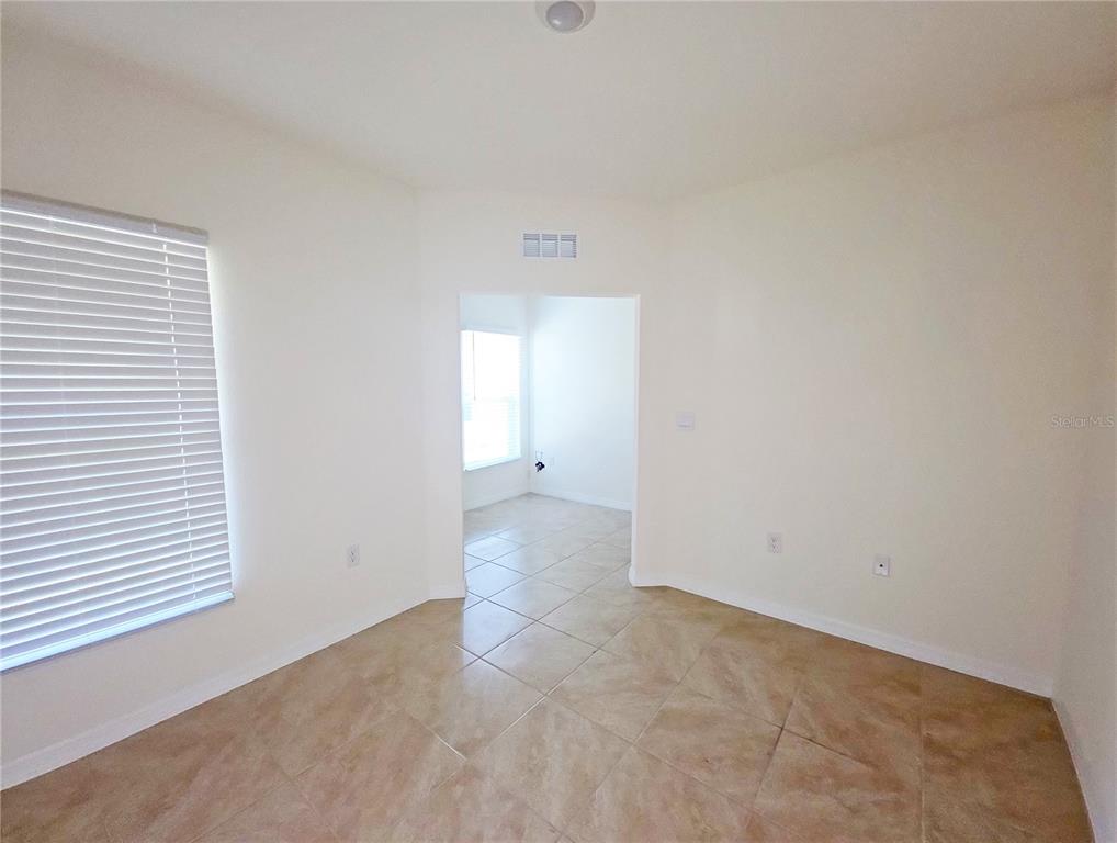 An empty room with beige tile flooring and a doorway leading to another bright space — 2936 SUNRIDGE LOOP, ST CLOUD, FL