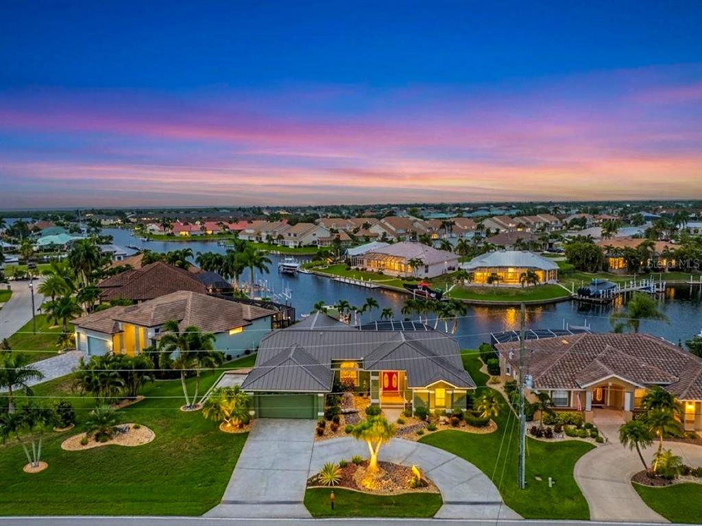 An aerial view of a waterfront house with a metal roof at sunset — 3601 WHIPPOORWILL BOULEVARD, PUNTA GORDA, FL