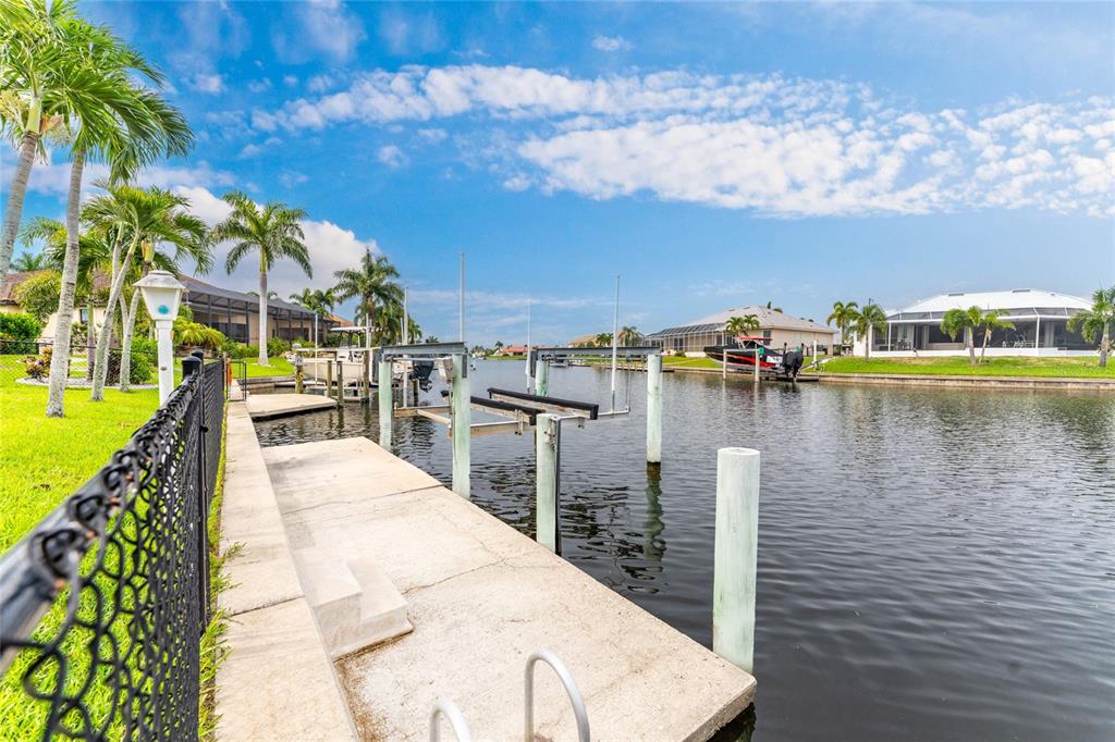 A concrete boat dock with a lift sits along a canal lined with palm trees — 3601 WHIPPOORWILL BOULEVARD, PUNTA GORDA, FL