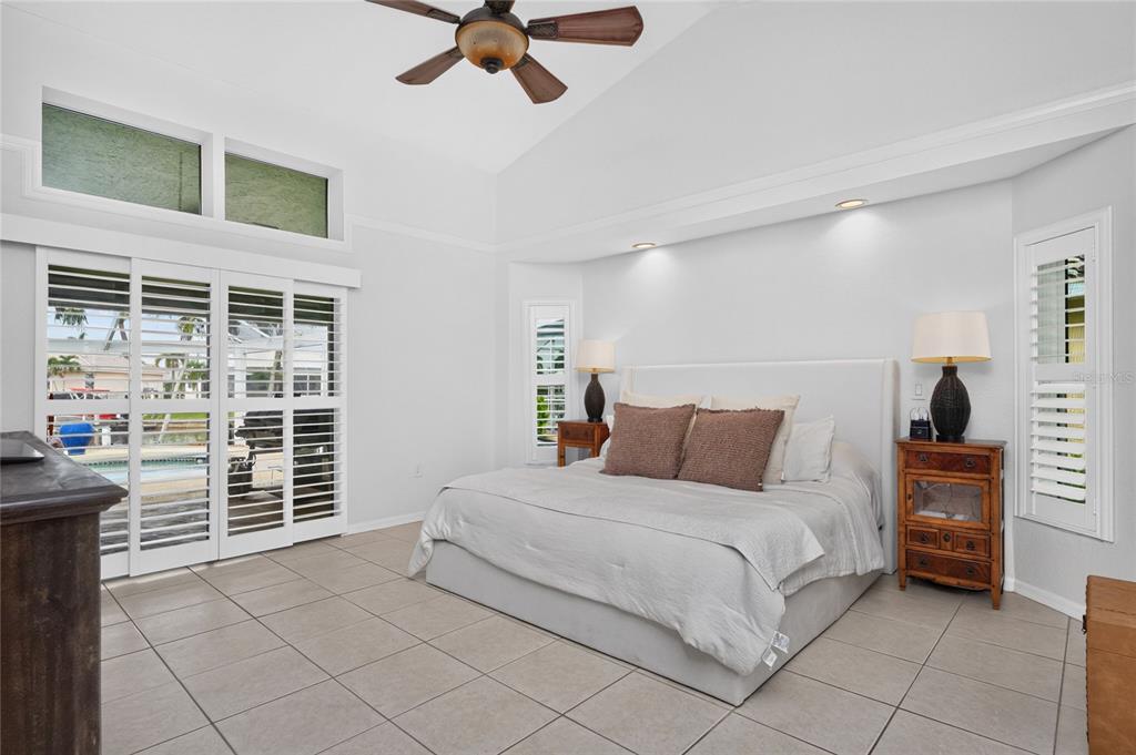 A bedroom with a vaulted ceiling, tile floors, a king bed, and sliding glass doors — 3601 WHIPPOORWILL BOULEVARD, PUNTA GORDA, FL