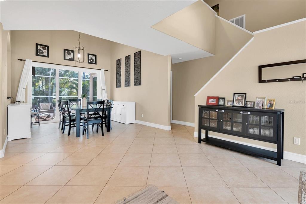 A dining area with a black table and chairs sits beside a tiled living space — 906 LANDMARK CIRCLE S, TIERRA VERDE, FL