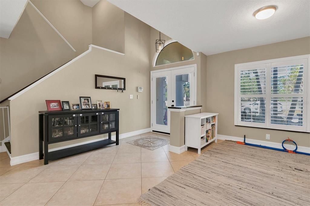 An entryway features tile flooring, a staircase, a black console table, and a white door — 906 LANDMARK CIRCLE S, TIERRA VERDE, FL