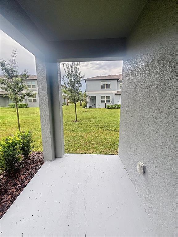 A view from a covered concrete patio looking out toward a grassy yard and houses — 14357 EASY GOER STREET, SUN CITY CENTER, FL