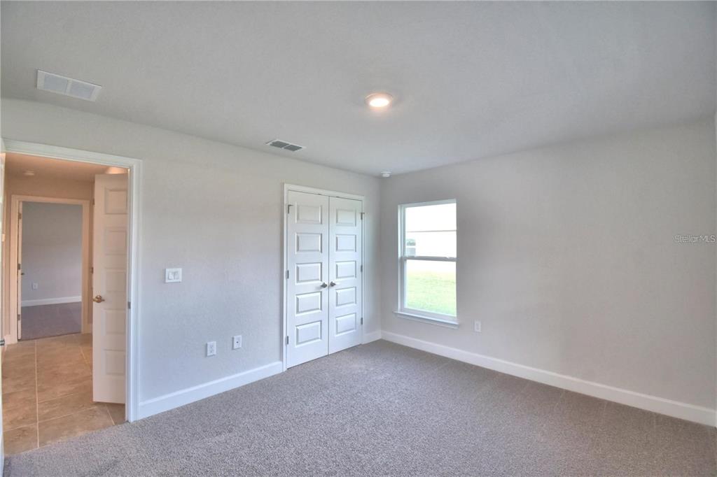A bedroom with gray carpet, light gray walls, a window, and a white closet door — 3636 LINDBERGH STREET, LAKELAND, FL