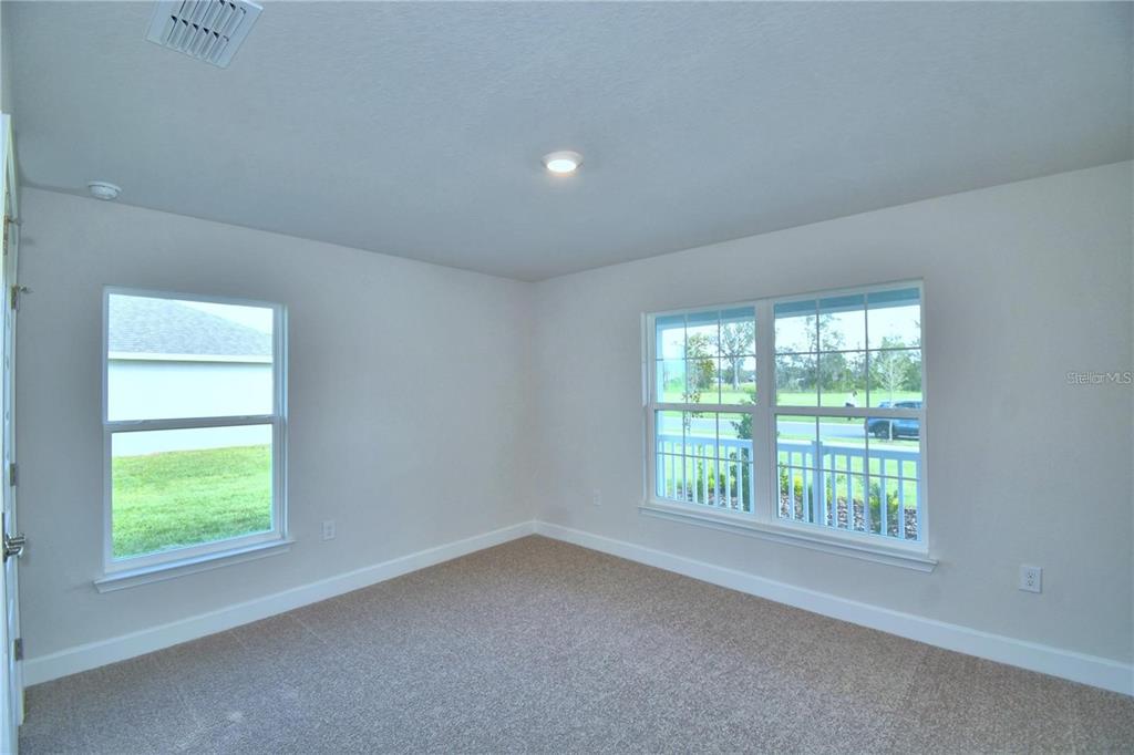 An empty room with beige carpet, white walls, and two windows overlooking a grassy yard — 3636 LINDBERGH STREET, LAKELAND, FL