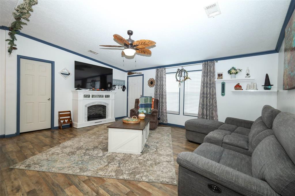 A living room features a fireplace, a grey sectional sofa, and a ceiling fan — 44031 EAST ROAD, PAISLEY, FL