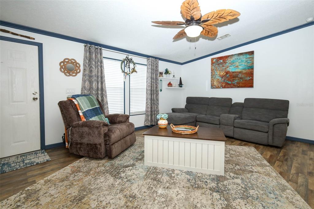 A living room features a gray sectional sofa, a brown recliner, and a coffee table — 44031 EAST ROAD, PAISLEY, FL