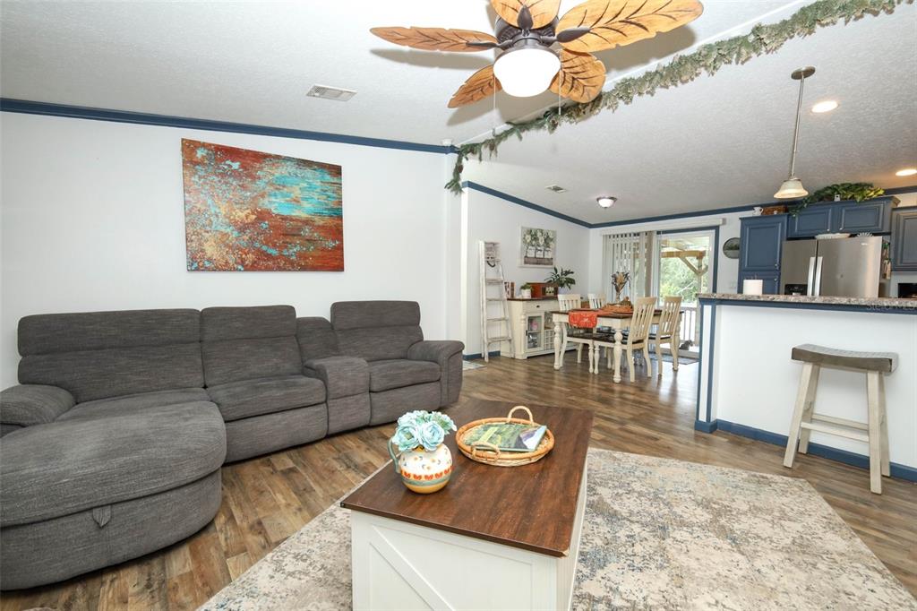 A living room with a gray sectional sofa, coffee table, and open-concept kitchen and dining area — 44031 EAST ROAD, PAISLEY, FL