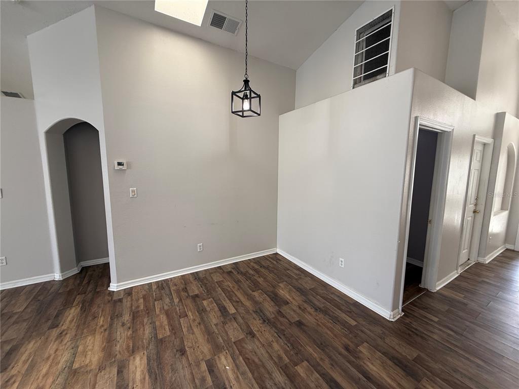 An empty room with wood-look flooring, a vaulted ceiling, and a hanging lantern light fixture — 16049 MAGNOLIA HILL STREET, CLERMONT, FL