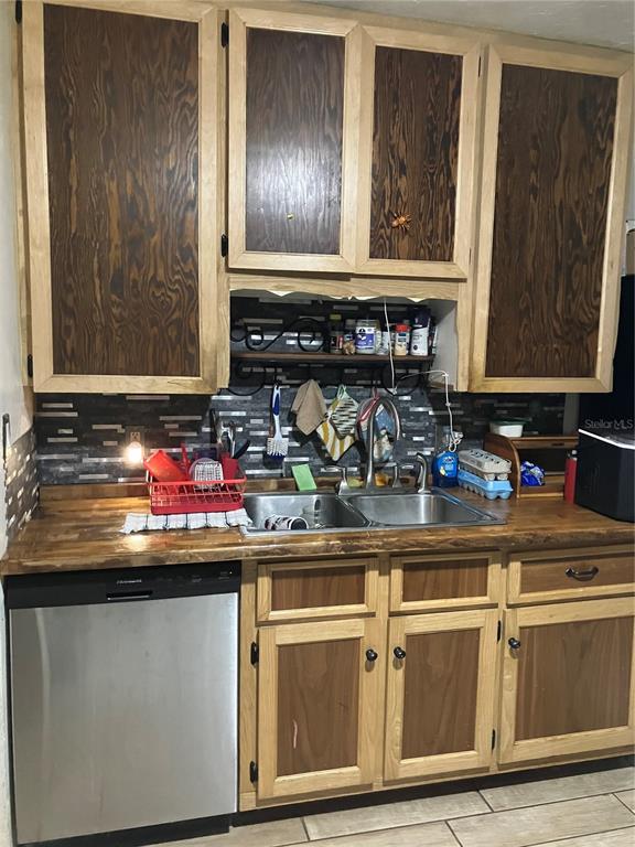 A kitchen features wood-trimmed cabinets, a stainless steel dishwasher, a double sink, and tiled backsplash — 3012 16TH AVENUE W, BRADENTON, FL