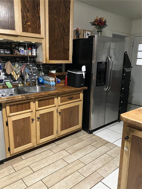 A kitchen features wood-trimmed cabinets, a stainless steel refrigerator, and wood-look tile flooring — 3012 16TH AVENUE W, BRADENTON, FL