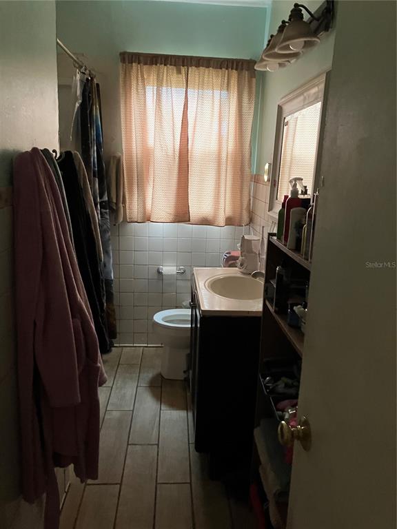 A bathroom features a vanity, a toilet, a shower curtain, and a window with curtains — 3012 16TH AVENUE W, BRADENTON, FL