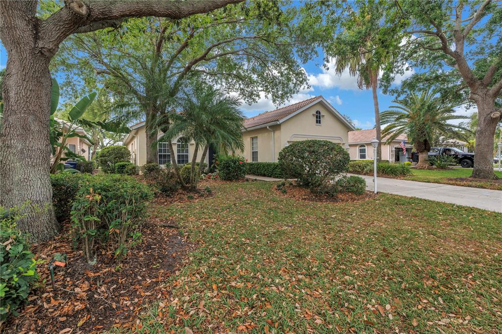 A single-story house with a beige exterior, a tiled roof, and a landscaped front yard — 4334 MIRABELLA CIRCLE, BRADENTON, FL