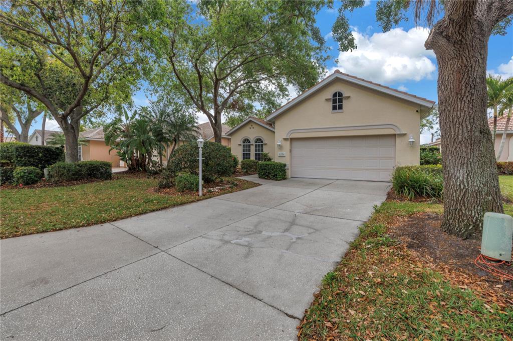 A single-story house with a beige stucco exterior, a two-car garage, and a concrete driveway — 4334 MIRABELLA CIRCLE, BRADENTON, FL