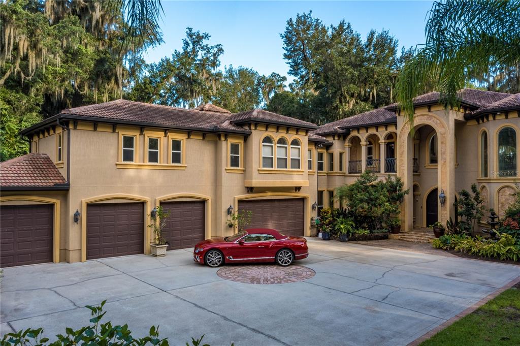 A large tan multi-story house with a three-car garage and a red convertible parked outside — 8289 COLEE COVE ROAD, ST AUGUSTINE, FL