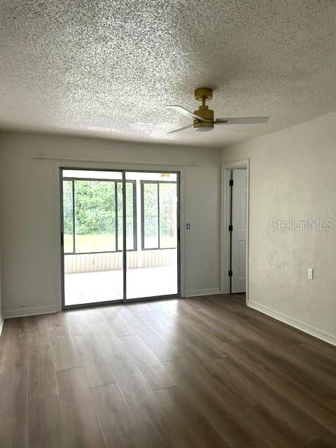 An empty room features dark wood-look flooring, white walls, and a doorway leading to another room — 1060 E NORMANDY BOULEVARD, DELTONA, FL