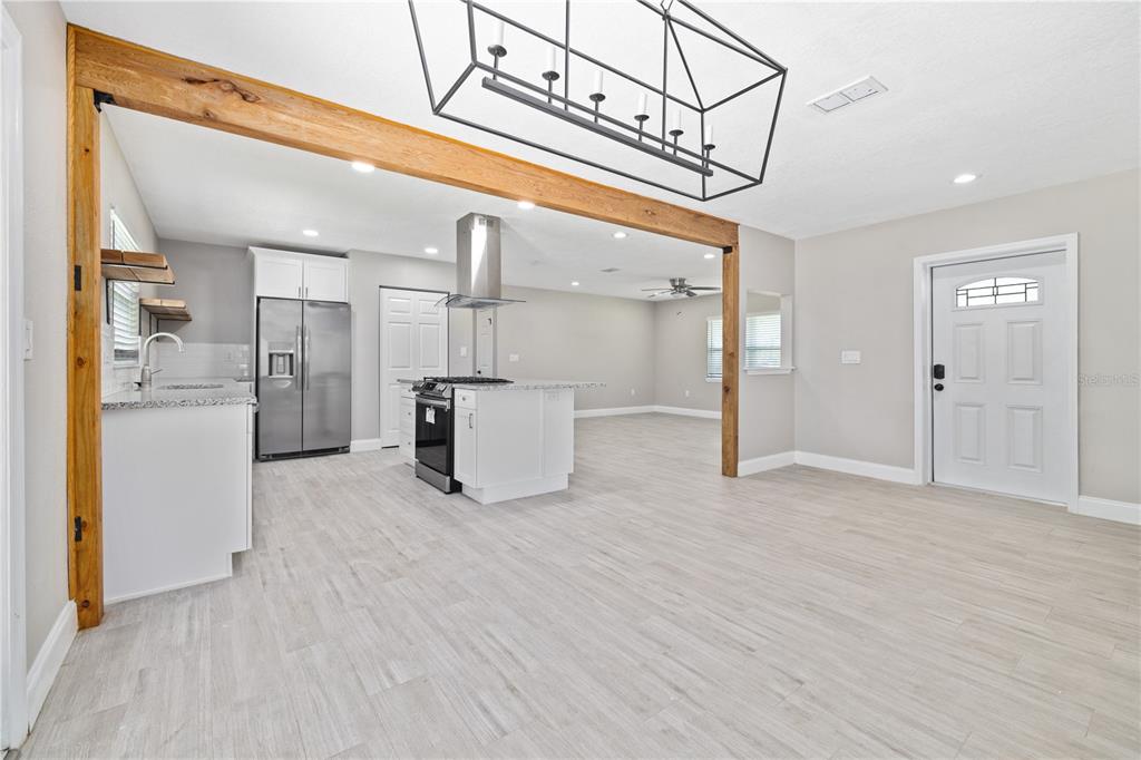 A kitchen with stainless steel appliances and a wooden beam opens into a living area — 408 W VIRGINIA AVENUE, TAMPA, FL