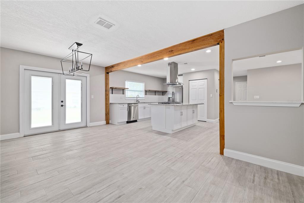 A kitchen with white cabinets and a center island sits behind a large wooden beam — 408 W VIRGINIA AVENUE, TAMPA, FL