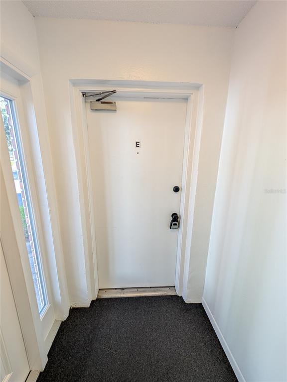 A white door labeled E with a lockbox is situated in a small entryway — 2564 SE 15TH AVENUE UNIT E, OCALA, FL