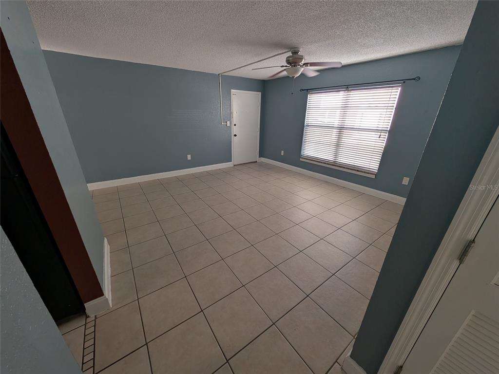 An empty room with blue walls, light tile flooring, a ceiling fan, and a window — 2564 SE 15TH AVENUE UNIT E, OCALA, FL