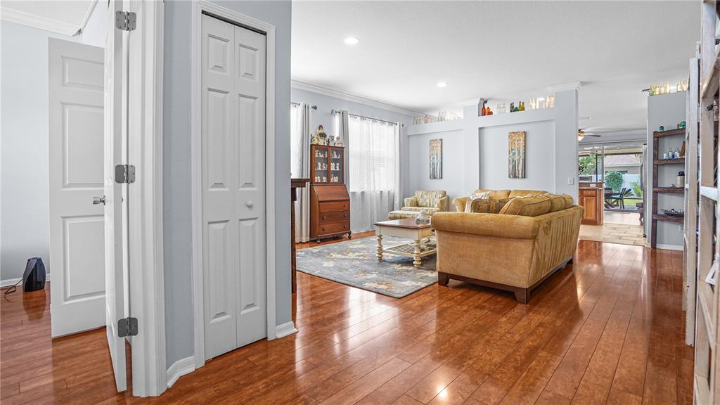 A living room with hardwood floors, a tan sofa, and a view into the kitchen — 19420 SUNSET BAY DRIVE, LAND O LAKES, FL