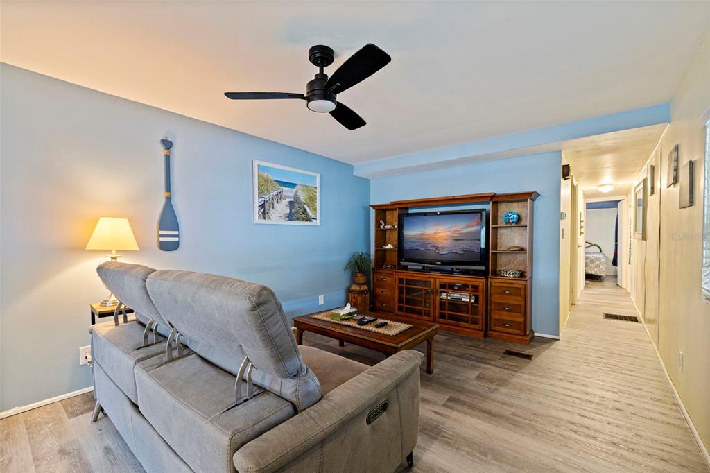 A living room features a brown sectional sofa, a wooden coffee table, and wood flooring — 6100 62ND AVENUE N UNIT 38, PINELLAS PARK, FL