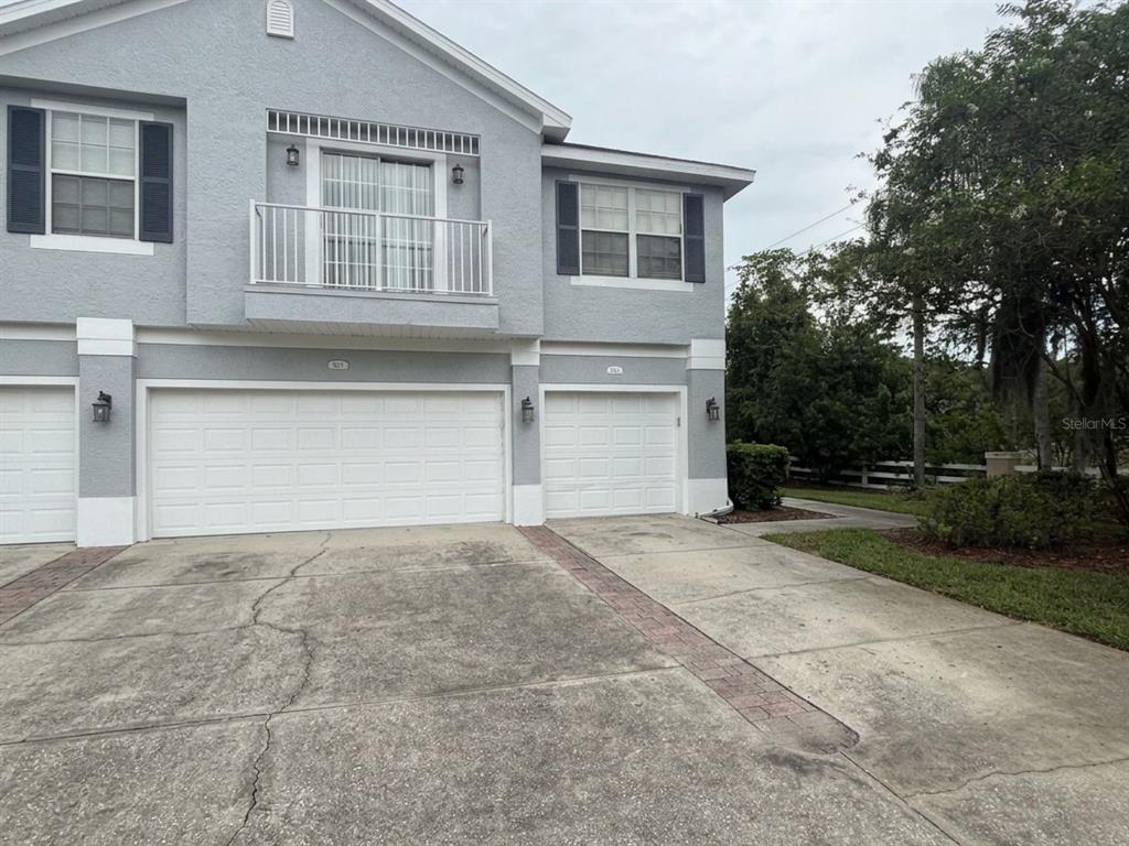 A two-story gray townhouse features two white garage doors and a second-story balcony — 8621 SHALLOW CREEK COURT, NEW PORT RICHEY, FL