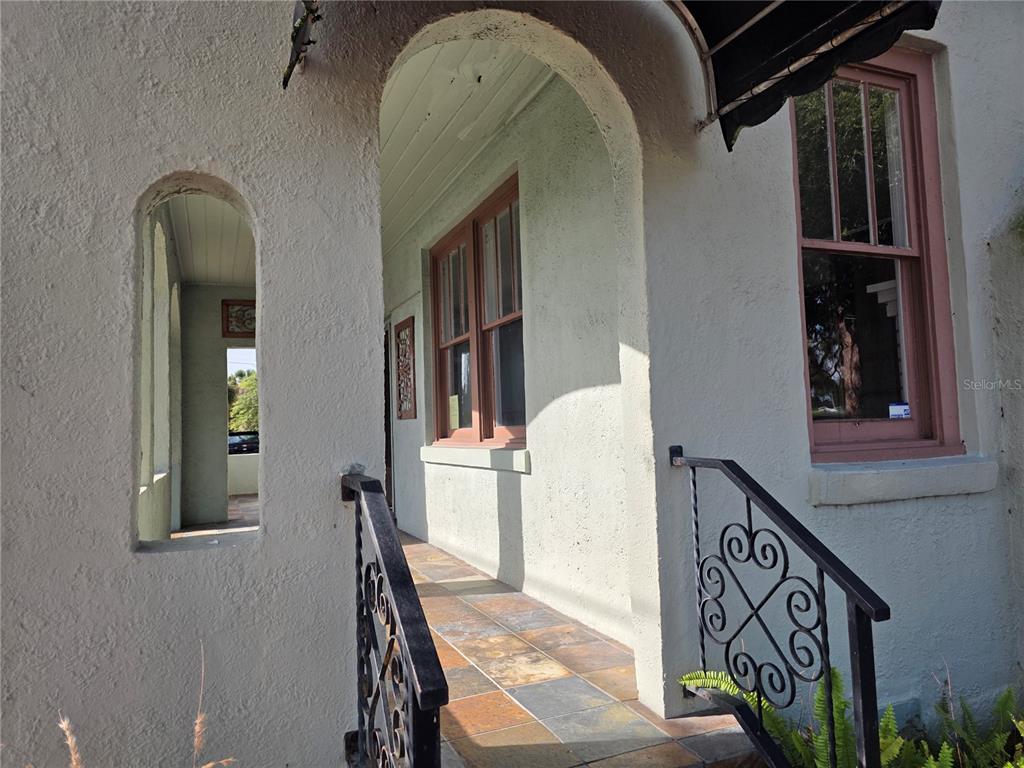 A covered porch with arched openings, tiled flooring, and decorative black metal railings — 1700 S WASHINGTON AVENUE, TITUSVILLE, FL