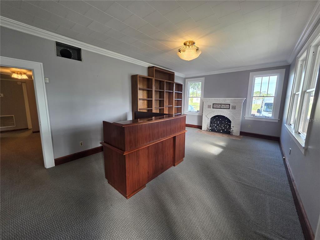 A room with gray walls, carpeted flooring, a wooden reception desk, bookshelves, and a fireplace — 1700 S WASHINGTON AVENUE, TITUSVILLE, FL