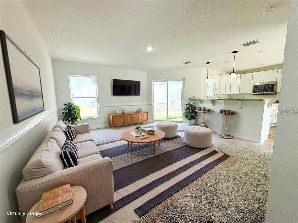 This living room features a sofa, a round coffee table, and an open kitchen area — 222 CARPENTERS WAY UNIT 66, LAKELAND, FL