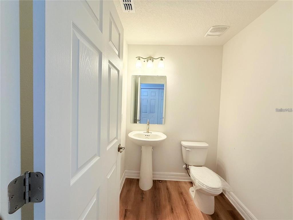 A small bathroom features a pedestal sink, a toilet, and a mirror on a wall — 222 CARPENTERS WAY UNIT 66, LAKELAND, FL