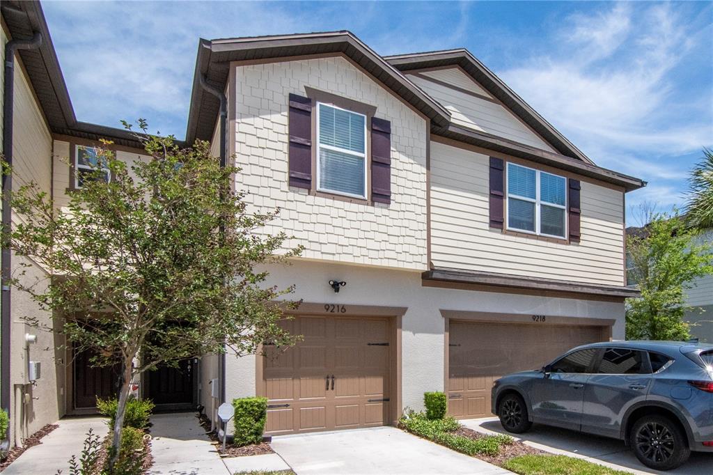 A two-story townhouse with a beige facade, brown garage doors, and a concrete driveway — 9216 HILLCROFT DRIVE, RIVERVIEW, FL