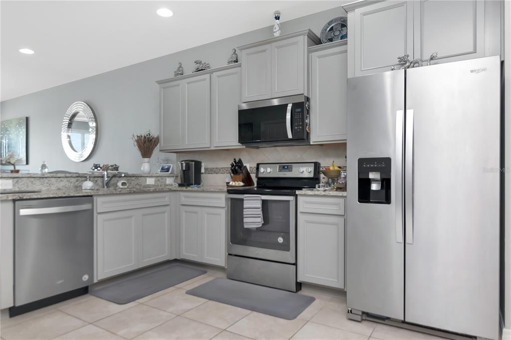A kitchen features gray cabinets, stainless steel appliances, and granite countertops — 9216 HILLCROFT DRIVE, RIVERVIEW, FL