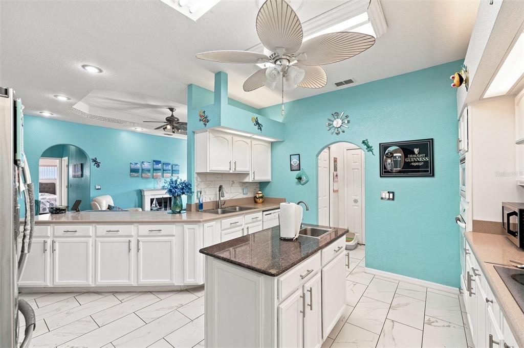 A kitchen with white cabinets, granite countertops, and turquoise walls features a central island — 13476 LITTLE FARMS DRIVE, SPRING HILL, FL