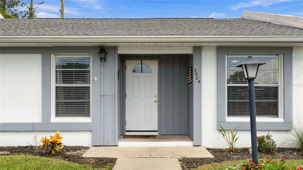 The exterior of a single-story house features a white stucco facade with grey trim — 3904 36TH AVENUE DRIVE W UNIT 37, BRADENTON, FL