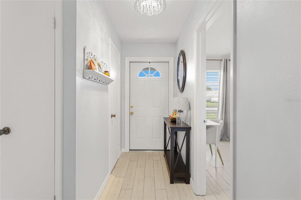 A bright entryway features light wood-look tile flooring, a white front door, and a console table — 3904 36TH AVENUE DRIVE W UNIT 37, BRADENTON, FL