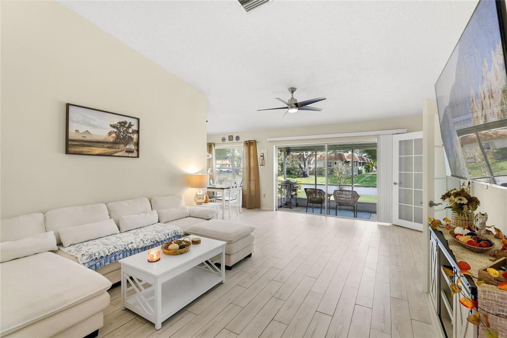 A living room features a white sectional sofa, a coffee table, and sliding glass patio doors — 3904 36TH AVENUE DRIVE W UNIT 37, BRADENTON, FL