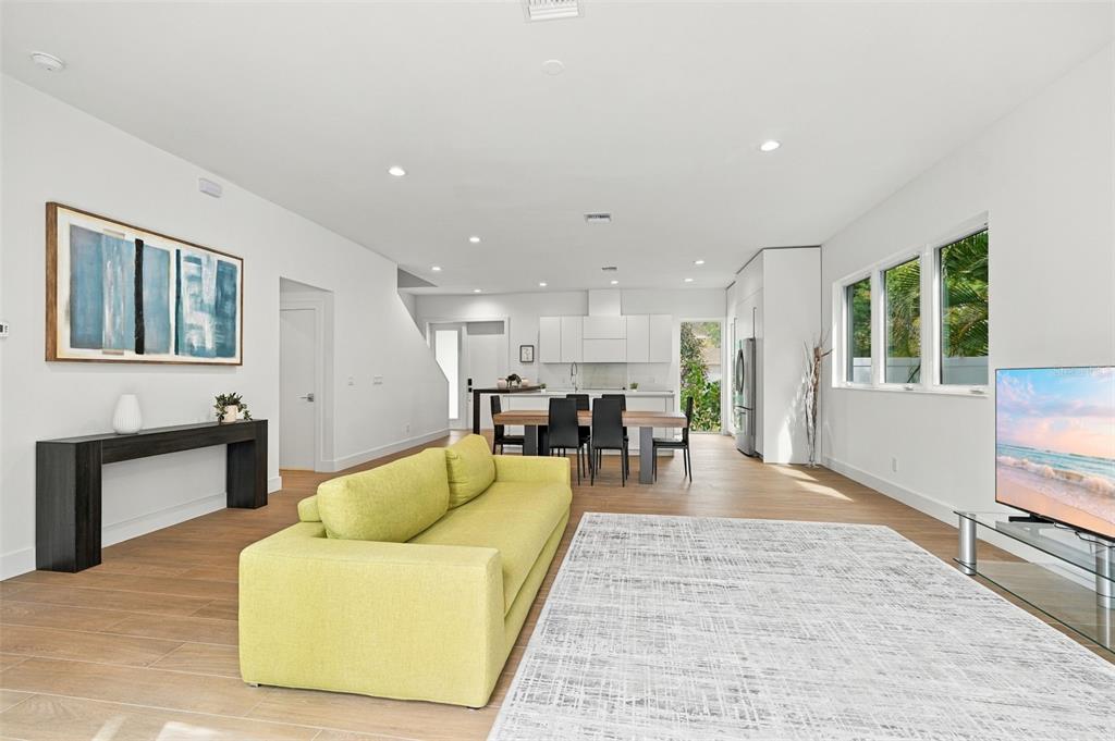 A modern, open-concept kitchen and living area with white cabinets and light wood flooring — 2516 BROWNING STREET, SARASOTA, FL