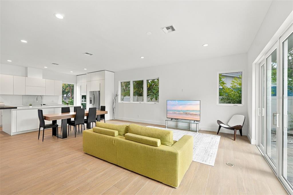 A modern kitchen features white flat-panel cabinetry, a central island with a dark wood breakfast bar — 2516 BROWNING STREET, SARASOTA, FL